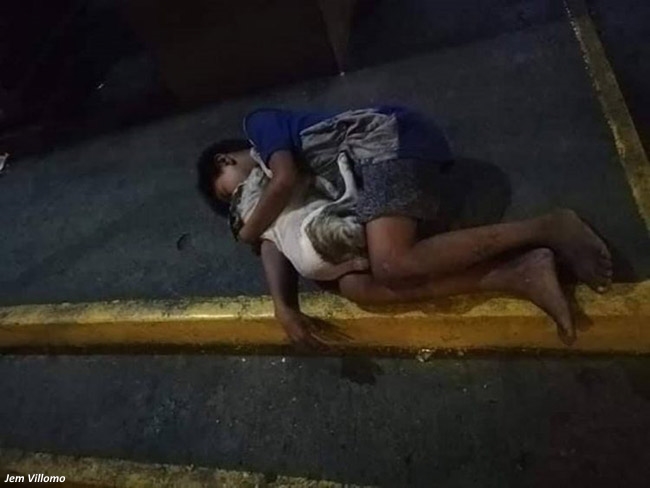 As a slumbering boy and his dog huddle together for warmth and affection, passersby casually stroll by, completely unaware of the heartwarming connection they share. - Puppies Love