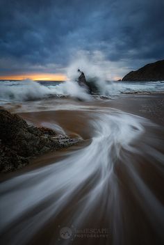 Phần này có thể chứa: the waves are crashing on the beach at night time, with dark clouds in the background