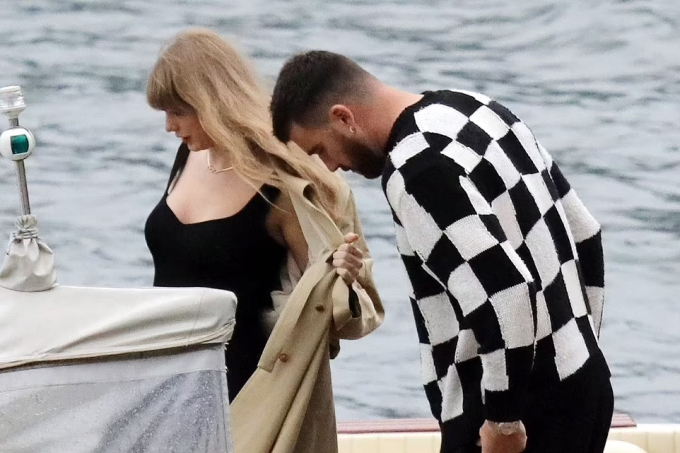Taylor wore a sexy, toned black dress with her boyfriend's black checkered t-shirt and black pants. She kept warm with a long coat.