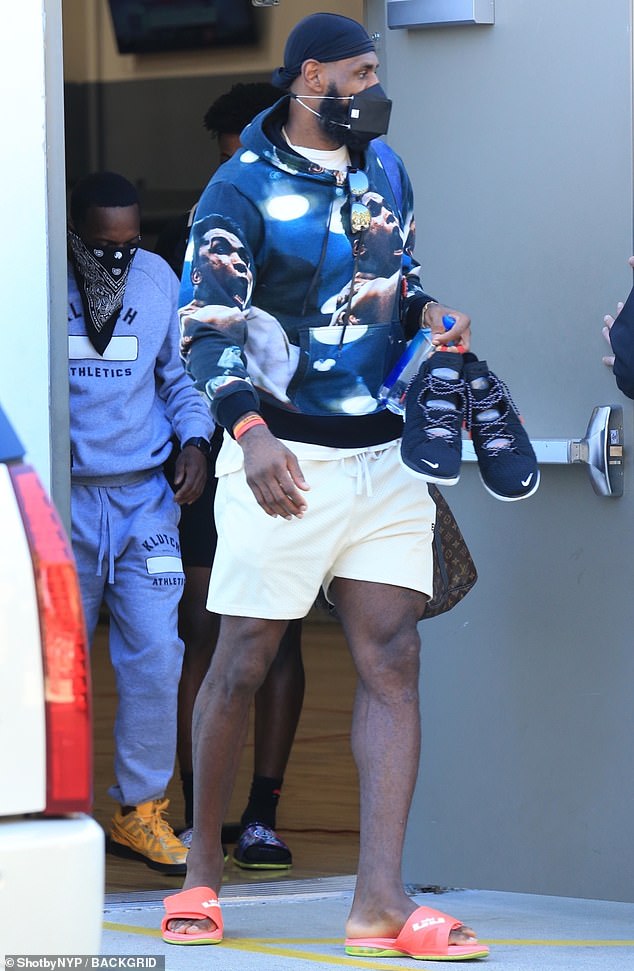 Channeling greatness: The 35-year-old sported a Muhammad Ali-printed hoodie with a pair of white ESNTLS basketball shorts and neon orange slip-on sandals with his King James logo